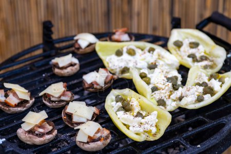 Photo for Grilled peppers with feta cheese and capers and mushrooms with bacon baked with Emmental cheese - Royalty Free Image
