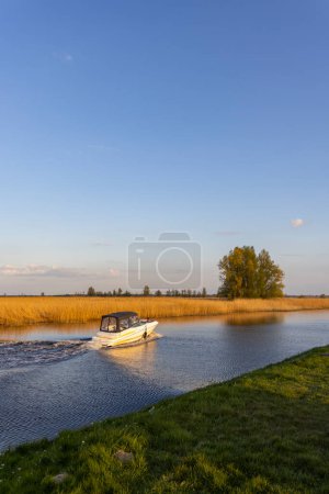 Photo for A water canal with a small boat nearby Steenwijk - Vollenhove  near Zwolle, The Netherlands - Royalty Free Image