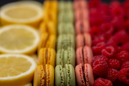 Téléchargez les photos : Macarons de différentes couleurs avec framboises et citron - en image libre de droit