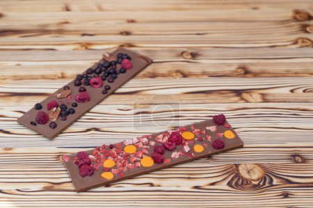 Foto de Diferentes tipos de chocolate con frutas secas en una tabla de madera - Imagen libre de derechos