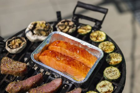 Foto de Carne de ternera, salmón y calabacín en parrilla de jardín con carbón vegetal - Imagen libre de derechos