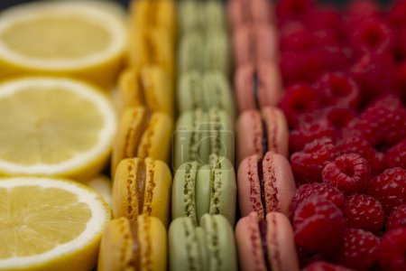 Téléchargez les photos : Macarons de différentes couleurs avec framboises et citron - en image libre de droit