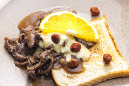 Téléchargez les photos : Mélange de bœuf avec sauce, noisettes et orange servi avec du pain grillé - en image libre de droit