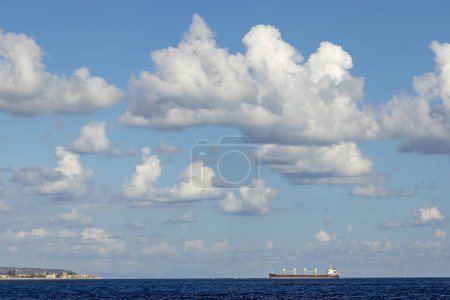 Foto de Buque de carga cerca del faro de Capo Peloro en Punta del Faro en el estrecho de Messina, promontorio más al noreste de Sicilia, Italia - Imagen libre de derechos