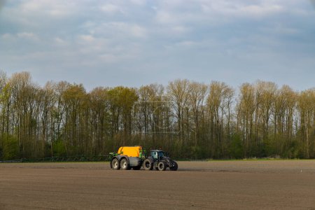 Tractor con pulverizador durante el trabajo de primavera en el campo