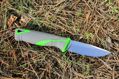 tourist survival knife against a background of pine needles in the forest