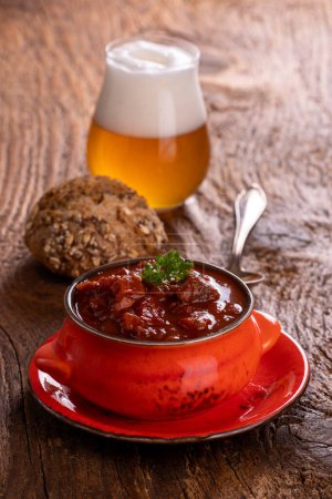 Photo for Goulash on dark wood with beer - Royalty Free Image