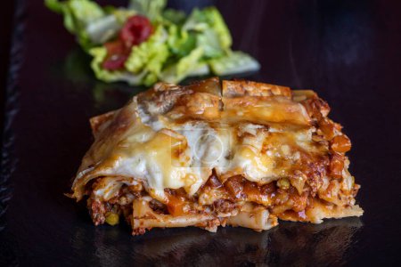 Téléchargez les photos : Portion of lasagna on black slate - en image libre de droit