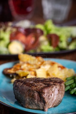 Téléchargez les photos : Steak avec gratin de pommes de terre et salade - en image libre de droit