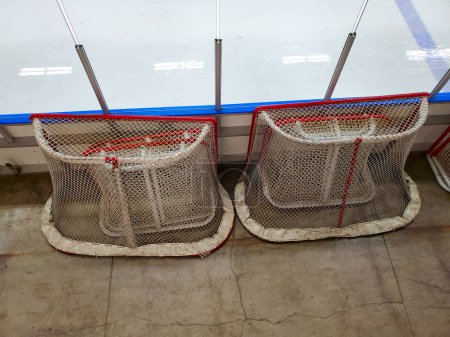 Hockey nets sitting at the side of a ice rink.