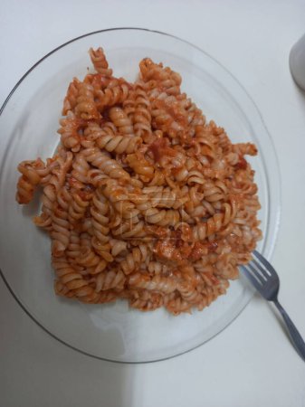Fusilli pasta with tomato sauce on a white plate with a fork