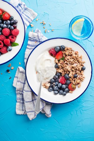 Téléchargez les photos : A plate of dry granola served with fresh berry fruit and yogurt. Oatmeal plate. Healthy food, diet. Top view. - en image libre de droit