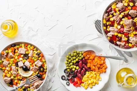 Téléchargez les photos : Salades de thon sain avec légumes mélangés en conserve sur fond de table blanc. Salade de maïs mexicaine. - en image libre de droit