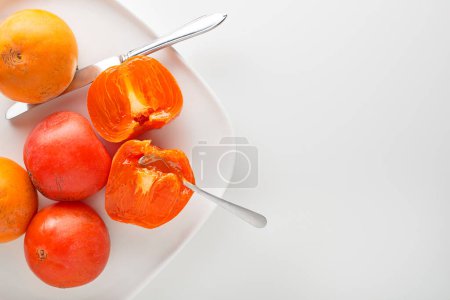 Foto de Fruta madura de caqui anaranjado rojo y amarillo.Trozos de caqui. Primer plano de kaki fresco sobre mesa blanca - Imagen libre de derechos