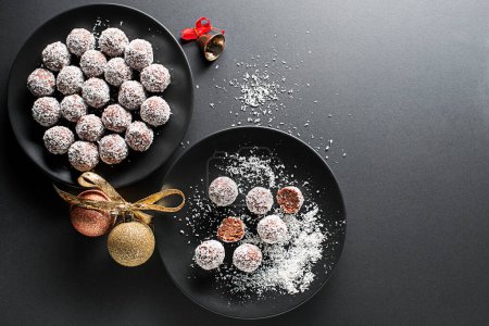 Foto de Deliciosas bolas de coco y chocolate cubiertas con coco rallado. Bolas de coco suaves, deliciosas y esponjosas con ron, galletas y chocolate. Concepto tradicional de galletas de Navidad - Imagen libre de derechos