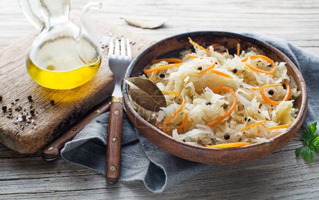 Téléchargez les photos : Homemade sauerkraut with carrot, black pepper and parsley in bowl on rustic background close up - en image libre de droit