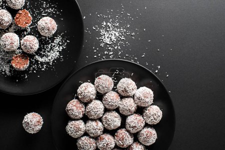 Foto de Deliciosas bolas de coco y chocolate cubiertas con coco rallado. Bolas de coco suaves, deliciosas y esponjosas con ron, galletas y chocolate. - Imagen libre de derechos