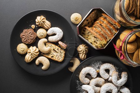 Foto de Tasty homemade sugar cookies and biscuits of all shapes and sizes on black table background - Imagen libre de derechos