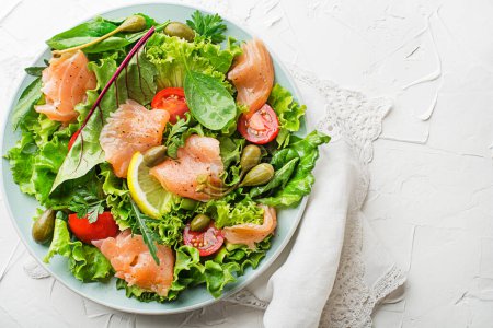 Photo for Fresh green salad with smoked salmon, cherry tomatoes and capers on white table background close up - Royalty Free Image