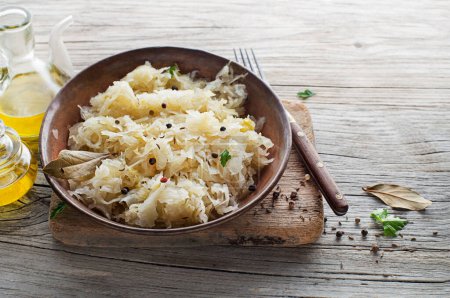 Photo for Homemade sauerkraut with black pepper and parsley in bowl on rustic background. Copy space. - Royalty Free Image