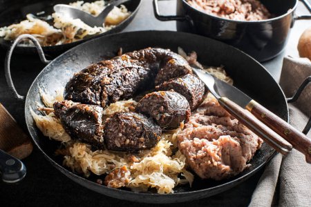 Photo for Bloody sausage morcilla, stewed sauerkraut and mashed potato with beans close up. Traditional Slovenian dish with roasted bloody sausage - Royalty Free Image