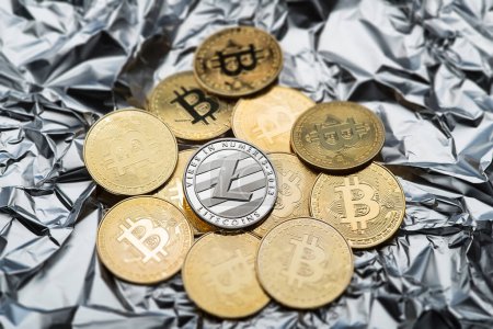 Foto de Bitcoin and cryptocurrency investing symbol concept. Litecoin and bitcoin on silver crumpled foil background. Trading on the cryptocurrency exchange. Trends in bitcoin exchange rates. - Imagen libre de derechos