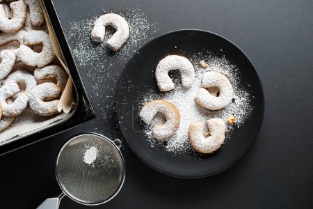 Photo for Baking Traditional vanilla crescents cookies and powdered with castor sugar. Holiday baking concept on black background - Royalty Free Image