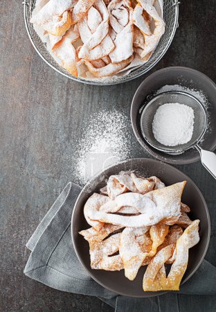 Téléchargez les photos : Pâtisserie sucrée croustillante traditionnelle - faworki ou ailes d'ange, frites et saupoudrées de sucre en poudre - en image libre de droit