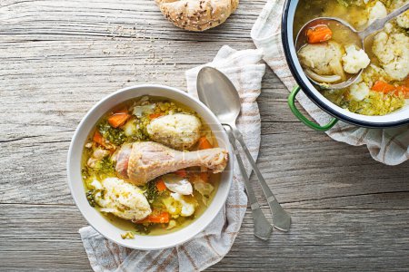 Photo for Fresh chicken soup with vegetable and semolina dumplings on wooden background overhead shoot - Royalty Free Image