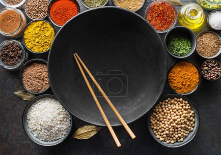 Téléchargez les photos : Ingrédients colorés avec des herbes et des épices pour la cuisson des repas. Épices asiatiques pour cuisine chinoise concept Sur fond de wok sombre. Vue du dessus. - en image libre de droit