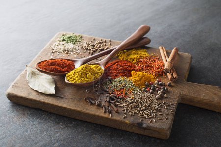 Foto de Coloridas hierbas y especias para cocinar la comida. Especias indias y asiáticas Sobre fondo de piedra gris. - Imagen libre de derechos