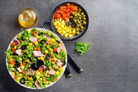 Téléchargez les photos : Salade verte saine avec thon, maïs, carottes, pois et olives sur fond de table gris. Salade de maïs mexicaine. - en image libre de droit