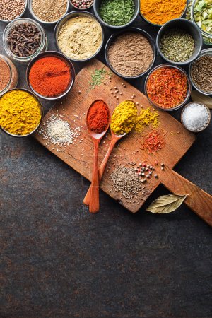 Colorful herbs and spices for cooking meal. Indian and asian spices On grey stone background. Top view.