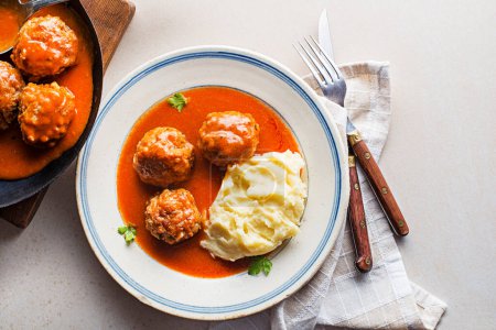 Téléchargez les photos : Fried meatballs braised in tomato sauce served with mashed potatoes on white table. Eating Beef roasted meatballs in tomato sauce. - en image libre de droit