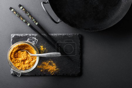 Photo for Turmeric powder(curcuma) is one of the key ingredients in many Asian dishes and wok- frying pan used typically in Chinese cooking - Royalty Free Image