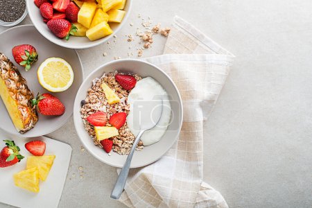 Photo for A bowl of dry granola served with fresh fruit and yogurt. Oatmeal plate. Healthy food, diet. Top view. - Royalty Free Image