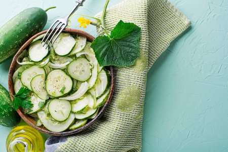 Fresh Cucumber salad with onion and dressing on green table background
