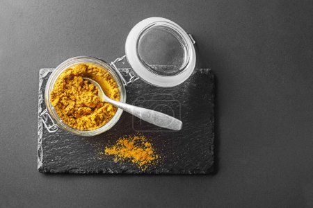 Foto de Curry powder (turmeric) in glass jar close up. Indian mixture of finely ground spices - Imagen libre de derechos