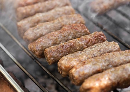 Photo for Grilling in barbecue of traditional south european skinless sausages cevapcici made of ground meat and spices outside in fireplace - Royalty Free Image