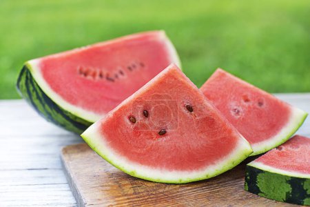 Photo for Fresh sliced watermelon in wooden table background outdoors - Royalty Free Image