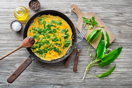 Photo for Spring omelette with fresh ramson or wild garlic leaves. Healthy spring diet food concept. - Royalty Free Image