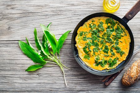 Spring omelette with fresh ramson or wild garlic leaves. Healthy spring diet food concept.