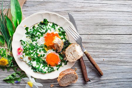Fried eggs with fresh spring plants and herbs. Healthy spring diet food concept.