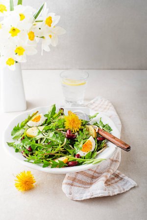 Photo for Dandelion salad with eggs, potato and beans on bright table background closeup - Royalty Free Image
