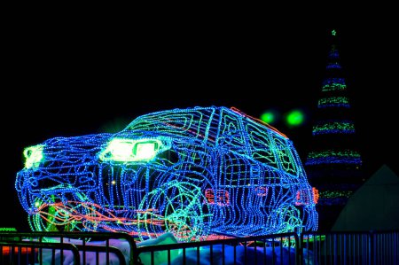 Téléchargez les photos : Arbre de Noël chic et une sculpture d'une voiture faite de néons brûlant en différentes couleurs sur fond de ville nocturne - en image libre de droit