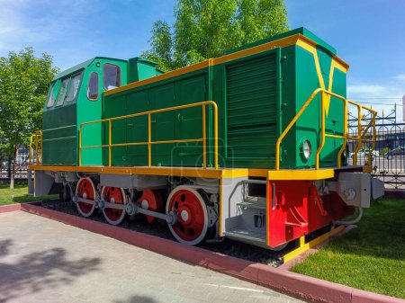 Foto de Pequeña locomotora diesel de derivación para el transporte de carga y pasajeros, primer plano sobre el fondo de los árboles y el cielo azul - Imagen libre de derechos