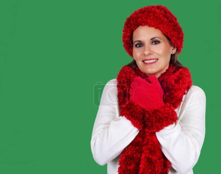 Foto de Hermosa mujer madura con suéter blanco con sombrero rojo, bufanda y guantes contra un fondo verde para la temporada de vacaciones - Imagen libre de derechos