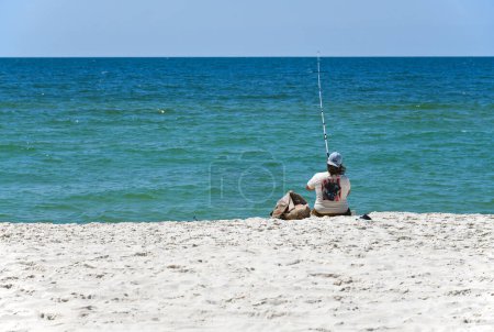 Foto de GULF SHORES, AL / USA - 3 de mayo de 2023: Joven pescando y disfrutando de un hermoso día soleado en Gulf Shores Beach en el Golfo de México - Imagen libre de derechos