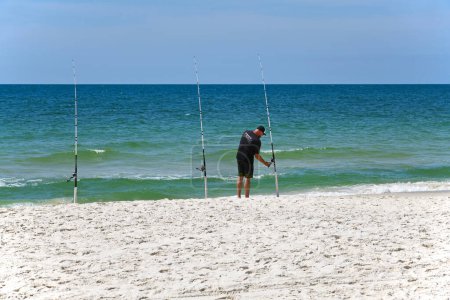 Foto de GULF SHORES, AL / USA - 3 de mayo de 2023: Joven pescando mientras disfruta de un hermoso día soleado en Gulf Shores Beach en el Golfo de México - Imagen libre de derechos