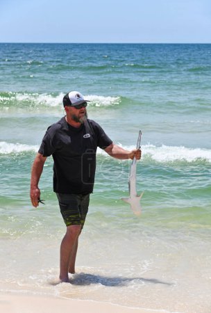 Foto de GULF SHORES, AL / USA - 3 de mayo de 2023: Joven sosteniendo un tiburón que capturó pescando en Gulf Shores Beach en el Golfo de México - Imagen libre de derechos